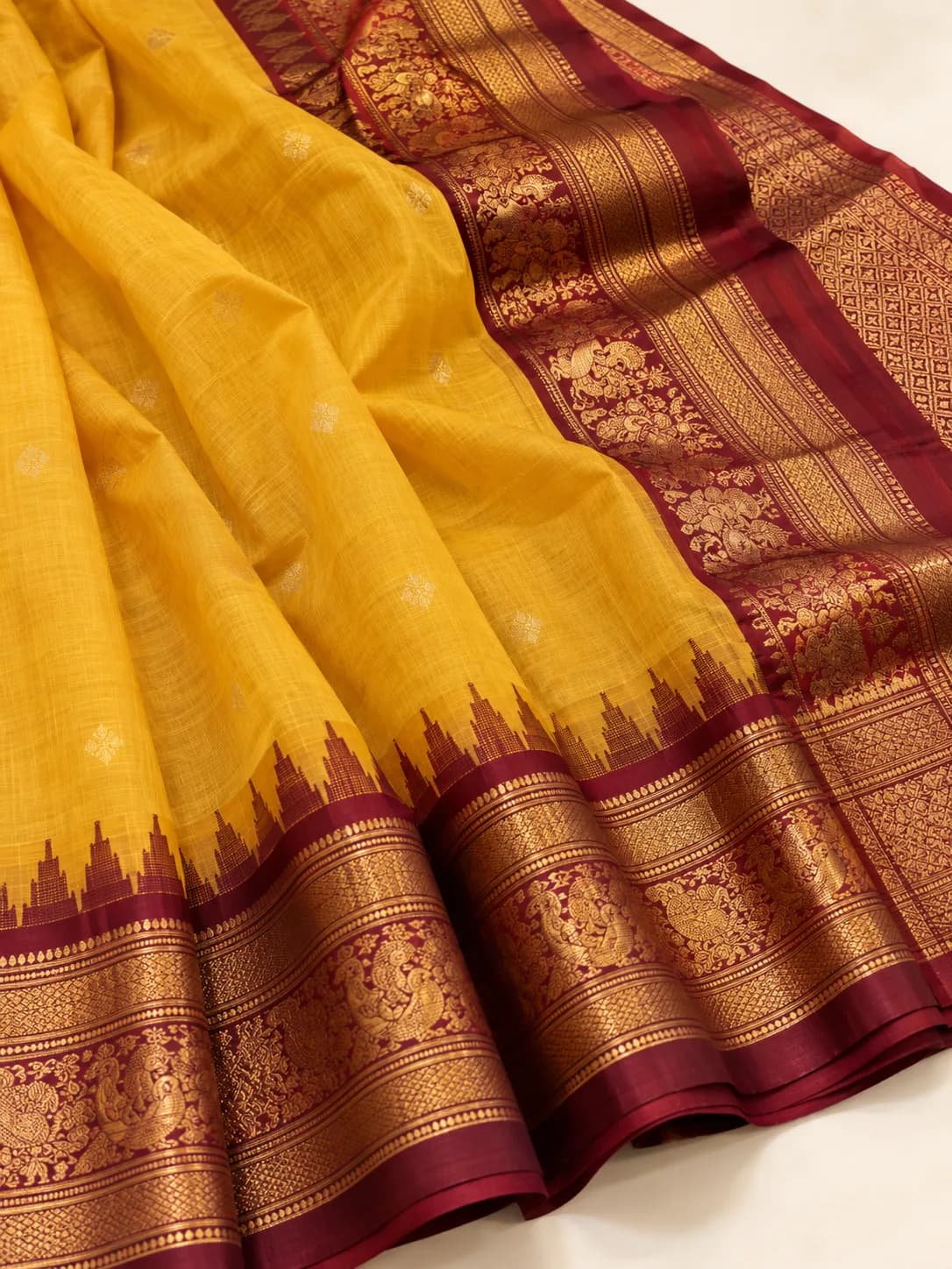 A yellow Gadwal saree with a cotton body and contrast maroon silk border and pallu