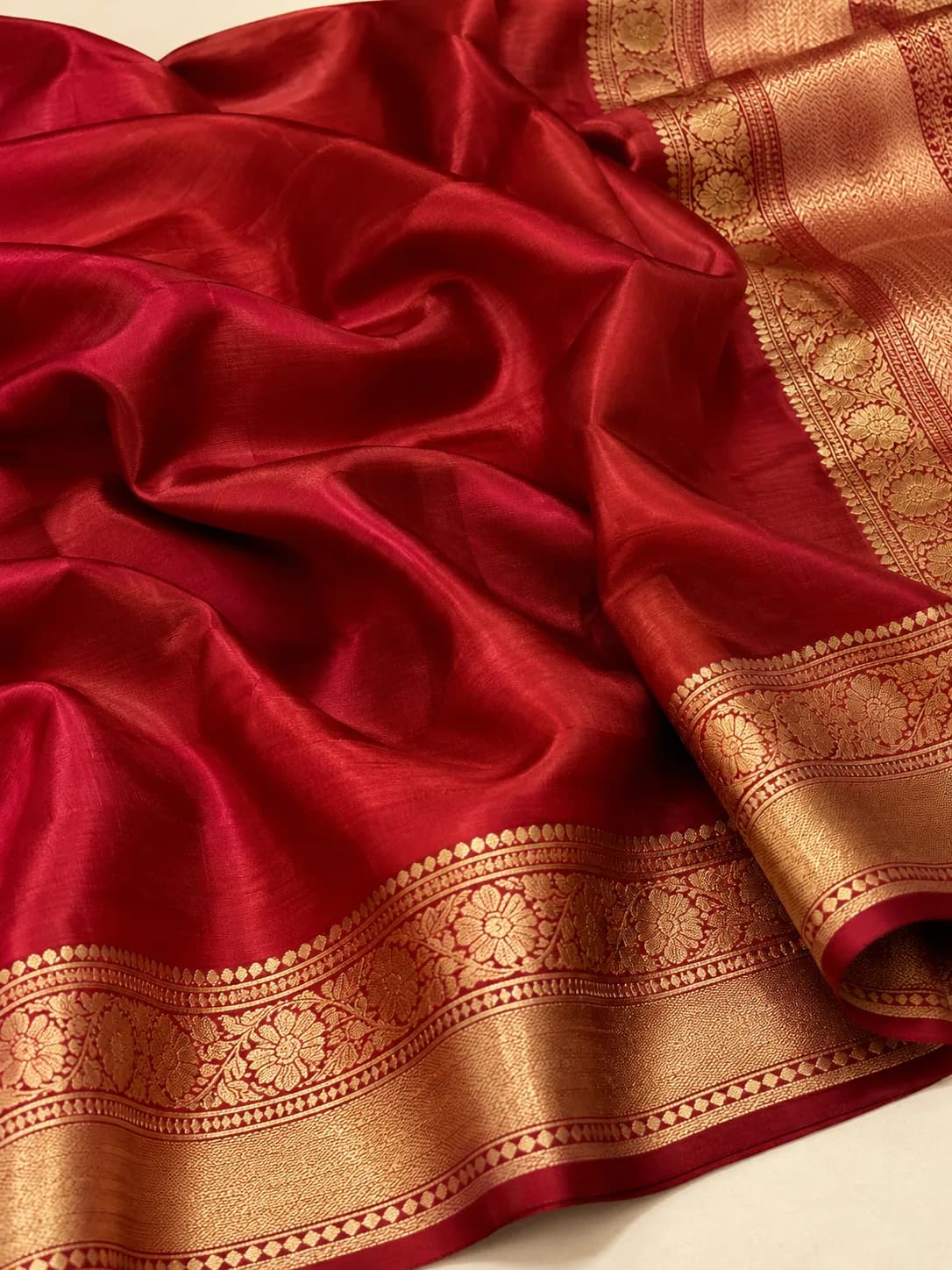 A Banarasi katan silk saree with a plain red silk ground and gold zari border
