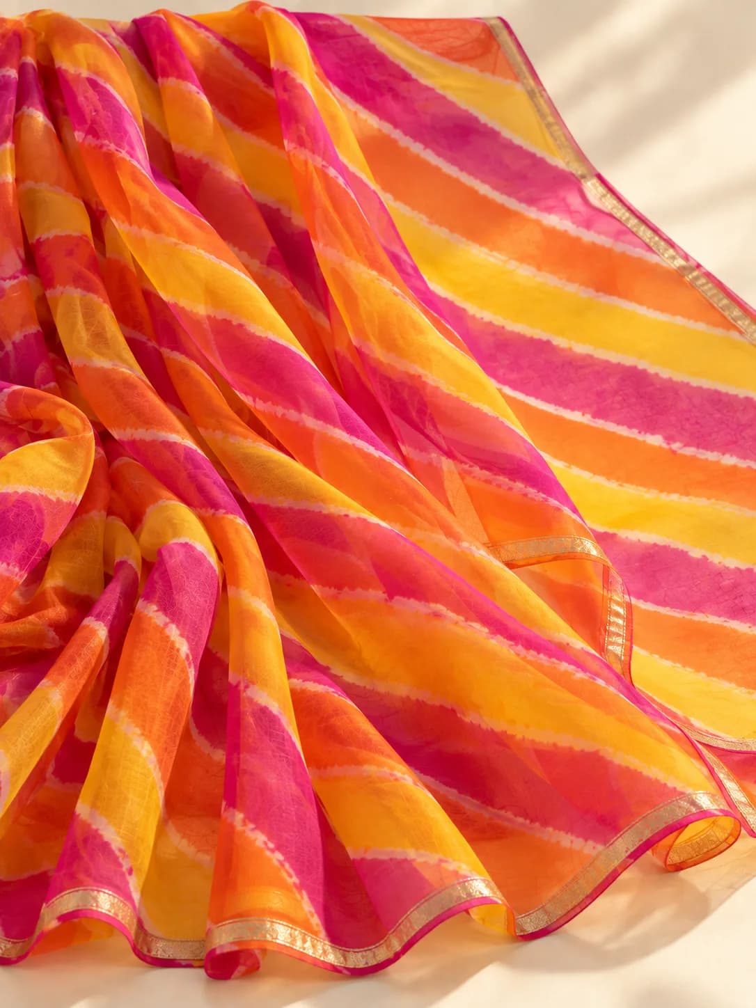 A Leheriya saree with diagonal tie-dyed stripes in pink, orange and yellow
