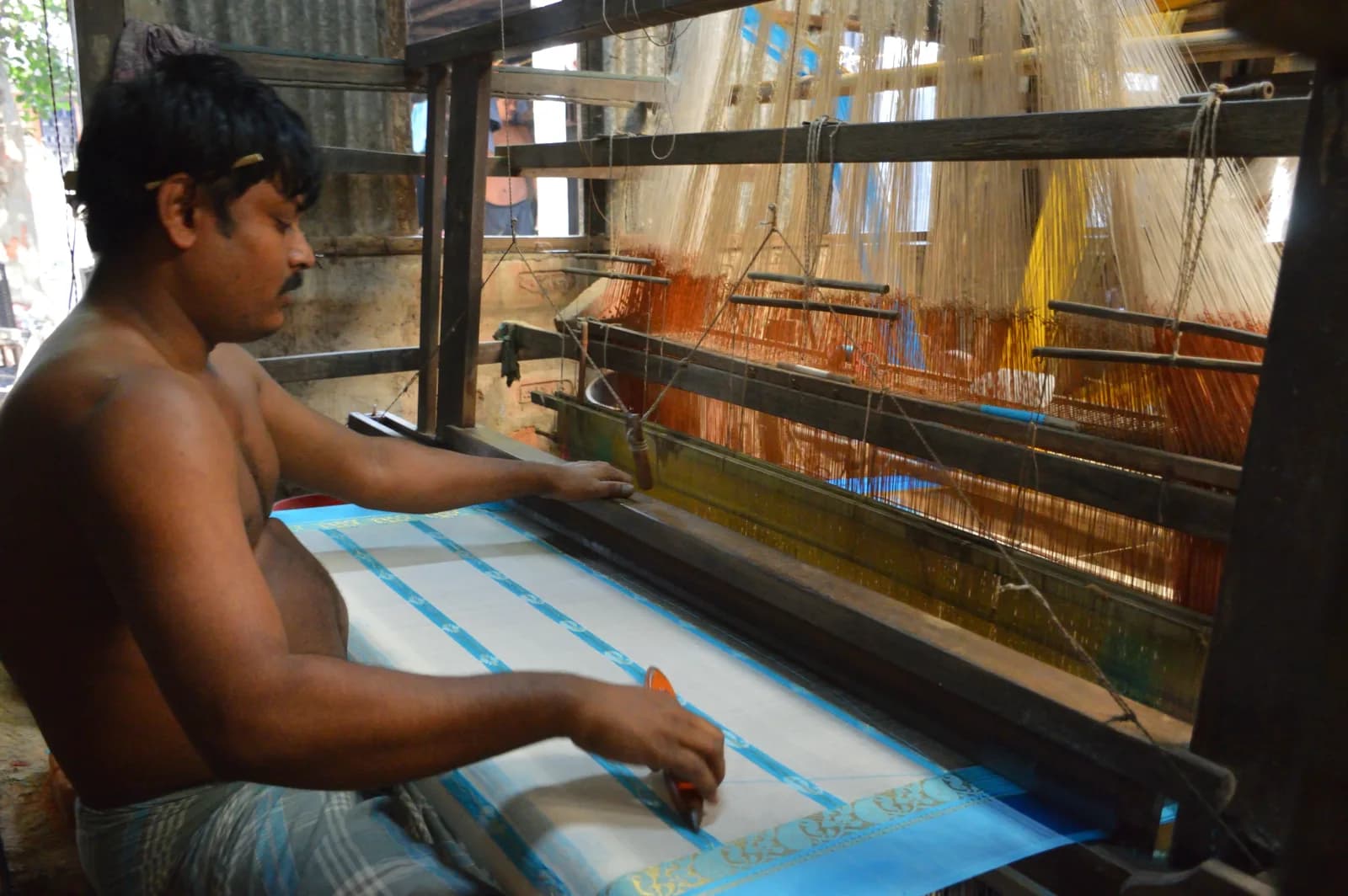 A weaver working a Tant saree on a handloom in Phulia, Nadia district, West Bengal