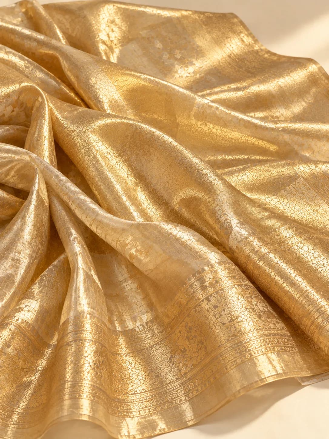 A gold tissue saree with metallic zari in the weft, giving the whole surface a shimmer